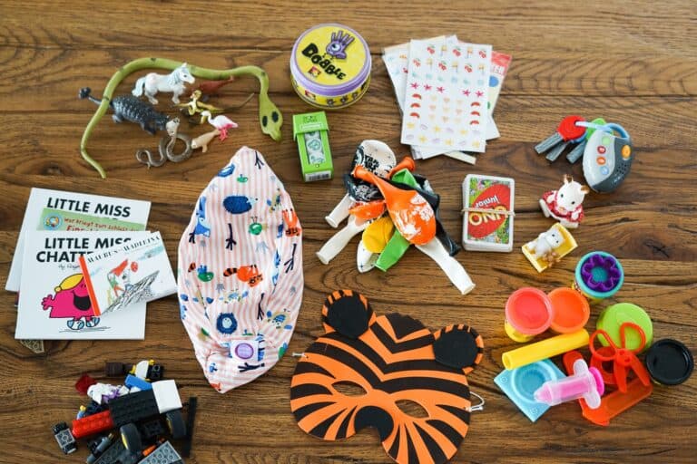 Stillleben aus Kinderspielzeug, u.a. Knete, Kartenspiele, Büchlein, Ballone, Spielfiguren - Ideen für Spielsachen für Reisen und Ferien