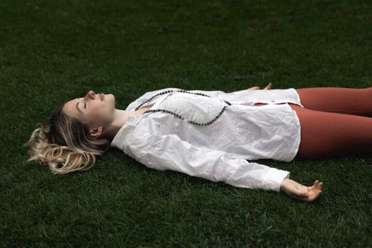 Die Journalistin Nadija Brenneisen liegt mit geschlossenen Augen auf einer Wiese - sie sagt: "Yoga Nidra hat mir das Leben gerettet!"