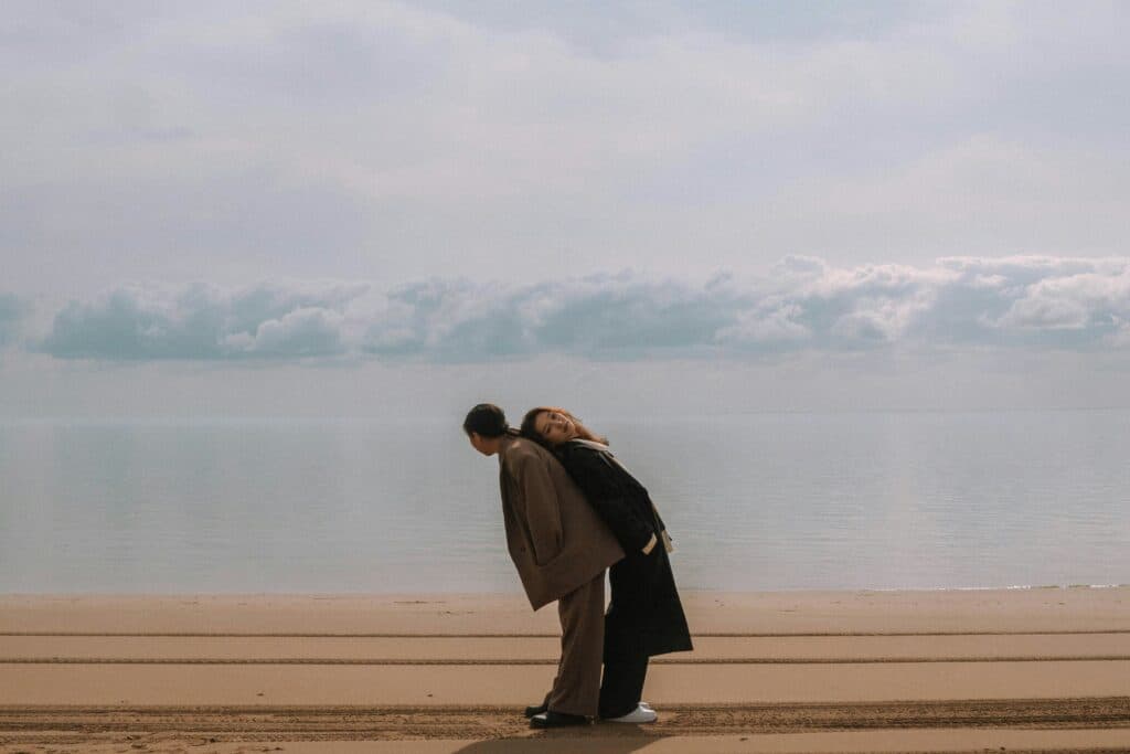zwei Personen im Sand stehend, die sich aufeinander abstützen. Ist Monogamie wirklich die passende Beziehungsform, die glücklich macht?