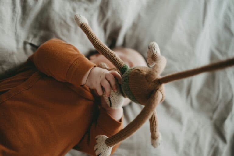 Baby spielt mit Kuscheltier. Es herrscht die Gefahr des Vercshluckens