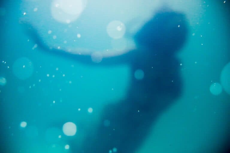 Frau schwimmt unter Wasser. Ein Trauma kann das Leben enorm beeinflussen.
