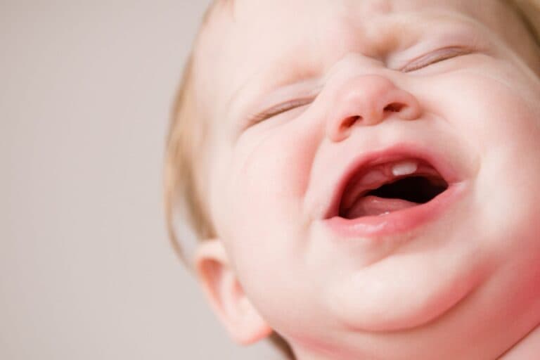Baby mit schmerzverzerrtem Gesicht. Zehnen kann sehr schmerzhaft sein und die ganze Familie belasten.
