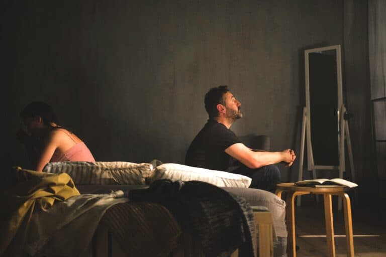 Ein Mann und eine Frau sitzen auf einem Bett, wenden einander den Rücken zu. Wenn eine Person keine Lust mehr empfindet, belastet das die Beziehung sehr.