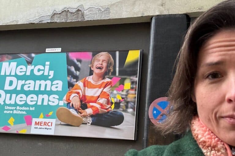Eine Frau steht vor einem Werbeplakat in Zürich. - In einer Werbung bezeichnet die Migros ein Kind als Dramaqueen, weil es emotional ist.