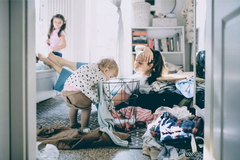 Eine Mutter schaut ihrem Kind erschöpft zu, wie es Wäsche im Zimmer verteilt. - Zum Weltfrauentag: Sind Frauen längst gleichberechtigt?
