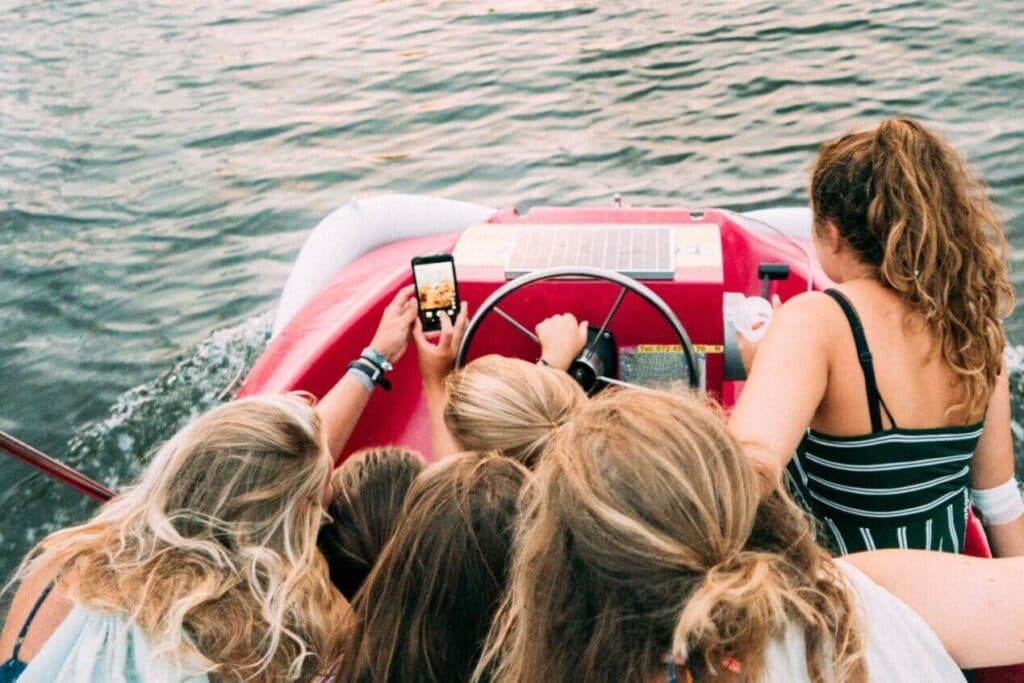 Jugendliche machen Selfies auf einem Pedalo. - Wie können Eltern die Medienkompetenz ihrer Kinder stärken?