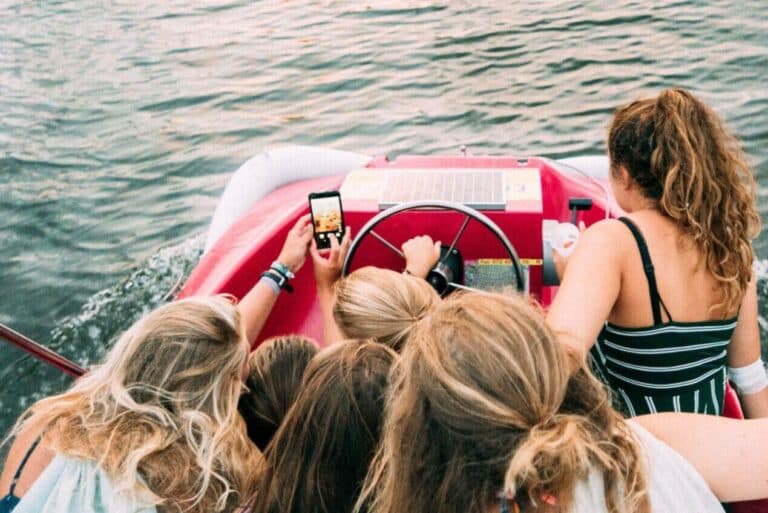 Jugendliche machen Selfies auf einem Pedalo. - Wie können Eltern die Medienkompetenz ihrer Kinder stärken?