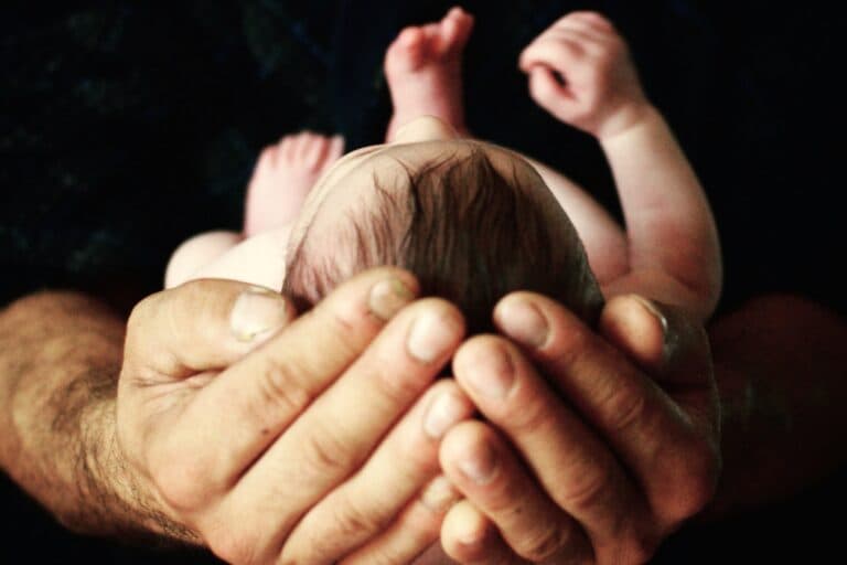 Vater hält Baby in der Hand. Vereinbarkeit ist für Väter schwierig - ein Mann erzählt.
