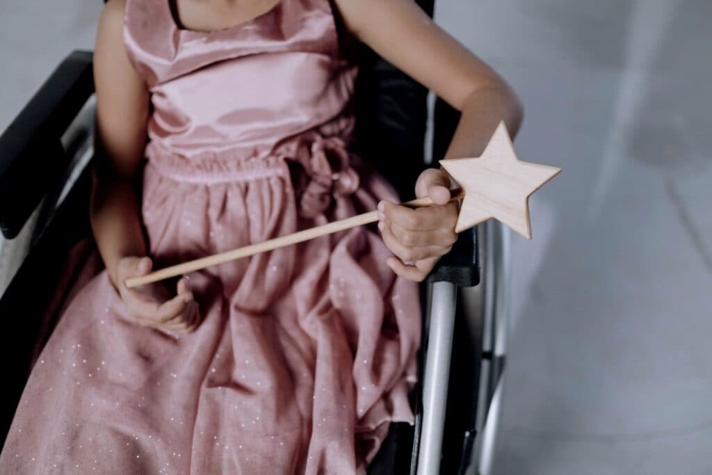 Mädchen im Rollstuhl mit Zauberstab in der Hand. - Familien mit einem Kind mit Behinderung und ihr Alltag zwischen Inklusion und Ableismus.