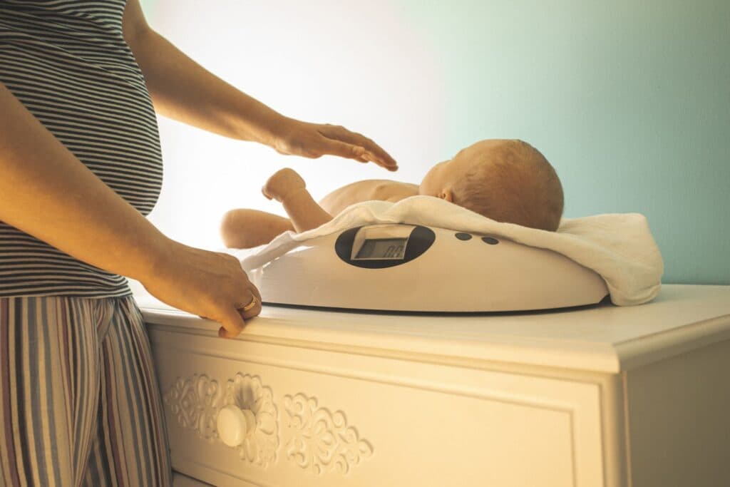 Baby auf einer Waage. Das Gewicht der Neugeborenen soll im Auge behalten werden.