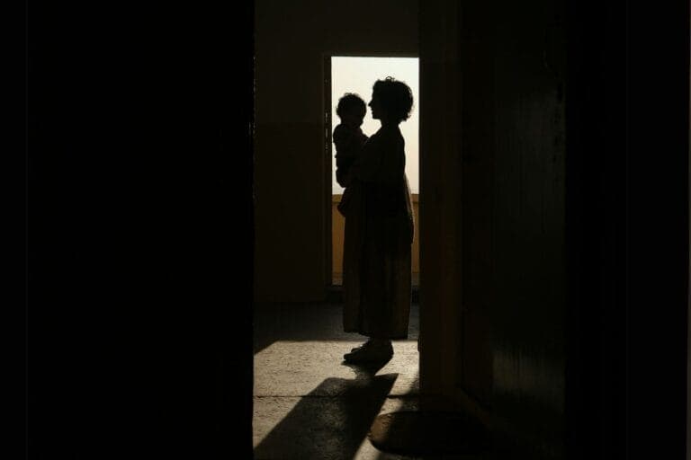 Eine Mutter mit Baby auf dem Arm, die im Gegenlicht nur als Silhouette sichtbar werden. Alleinerziehende sind oft gefangen in der Einsamkeit