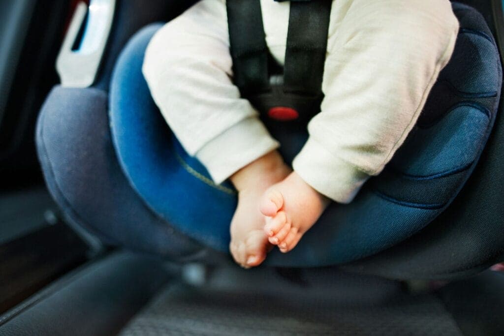 Beine und Füsse eines Babys, das in einem blauen Autokindersitz angeschnallt ist. - Wie finde ich den richtigen Kindersitz? Was ist Isofix?