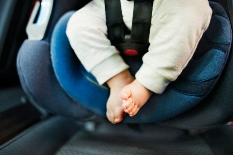 Beine und Füsse eines Babys, das in einem blauen Autokindersitz angeschnallt ist. - Wie finde ich den richtigen Kindersitz? Was ist Isofix?
