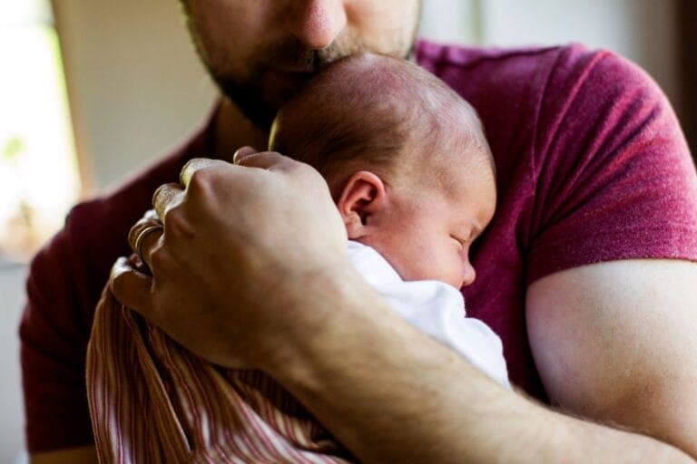 Ein Mann hält ein schlafendes Neugeborenes eng an die Brust - Was macht eigentlich einen Vater aus? Erfahrungsbericht eines Neuvaters