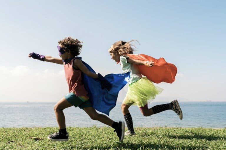 Junge und Mädchen rennen mit Superhelden-Umhang über eine Wiese. - Typisch Mädchen, typisch Jungs? Genderdiskussionen mit einem Erstklässler